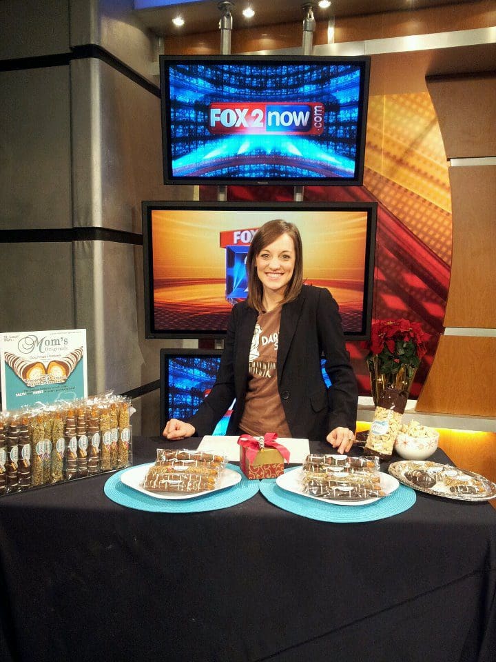 A woman standing behind a table with food on it.