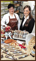 Two women standing next to a table filled with food.