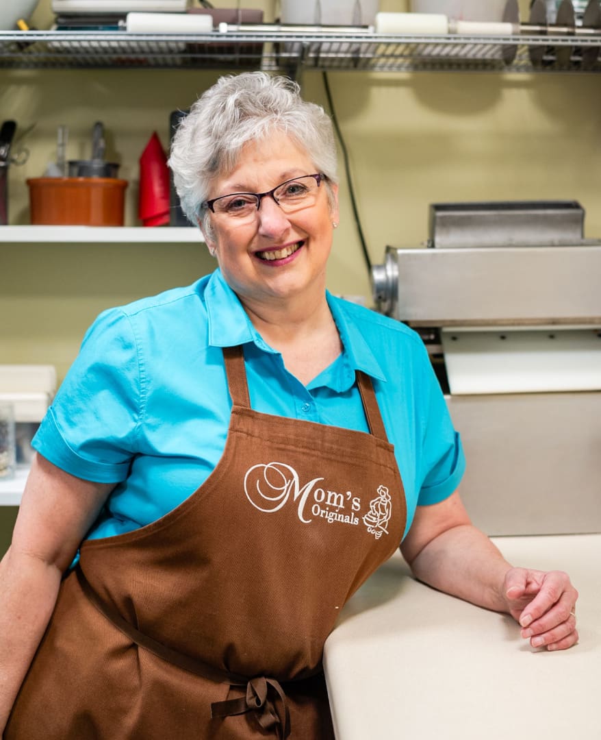 A woman in an apron standing at the counter.